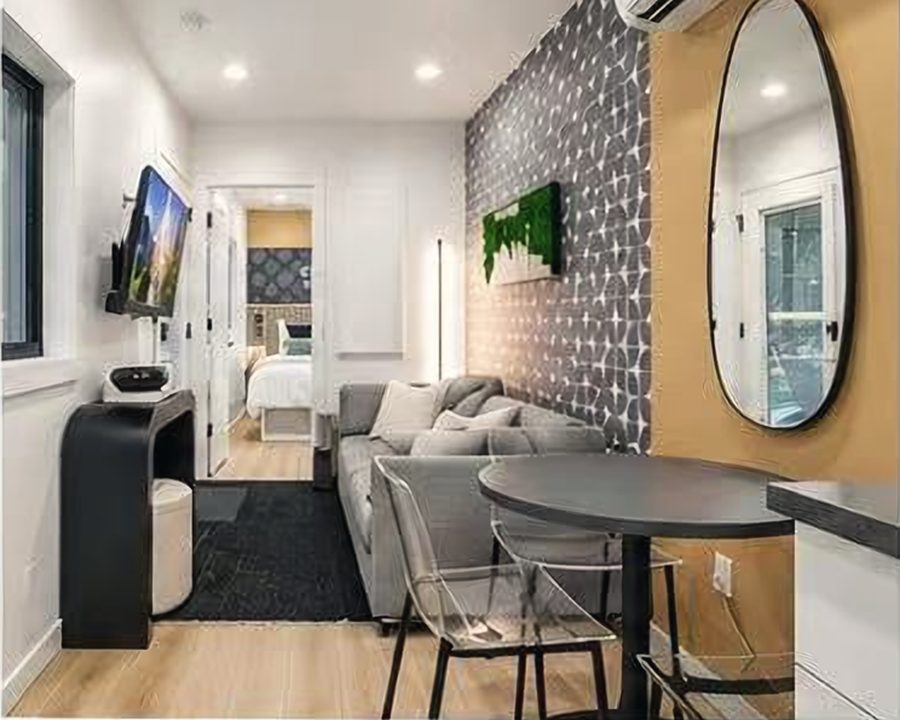Finished living room with sofa, dining table and a view through to the bedroom
